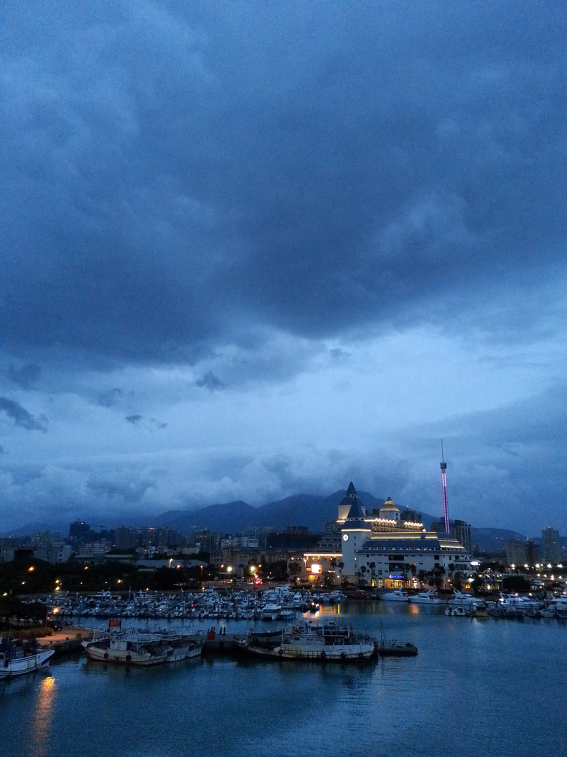 A photo of a harbor with boats and a building with a dome, taken during the evening.